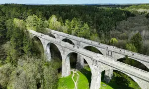 Kamienne wiadukty, dawna ścieżka rowerowa trasą kolejki wąskotorowej, otoczone bujnym lasem.