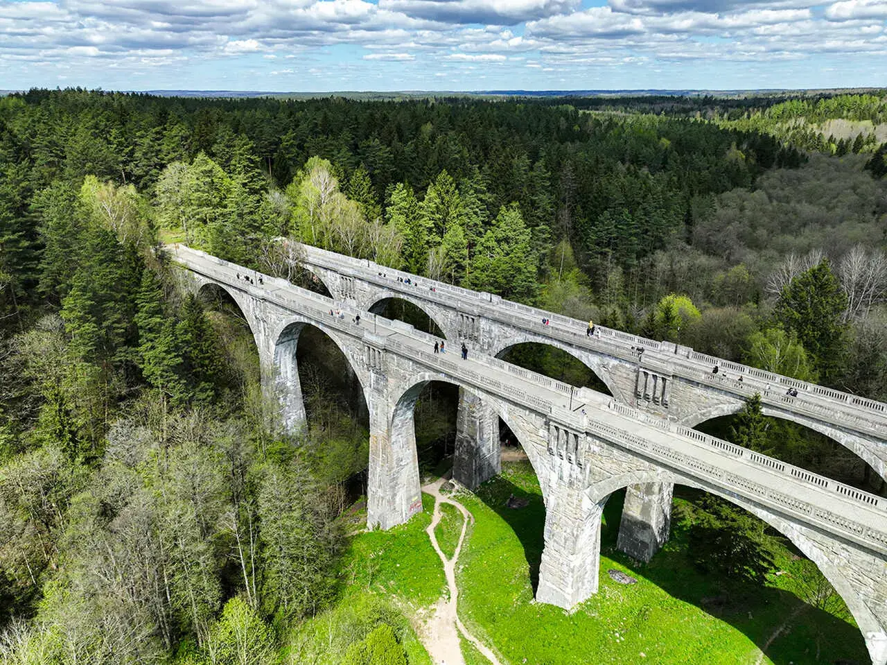 Kamienne wiadukty, dawna ścieżka rowerowa trasą kolejki wąskotorowej, otoczone bujnym lasem.