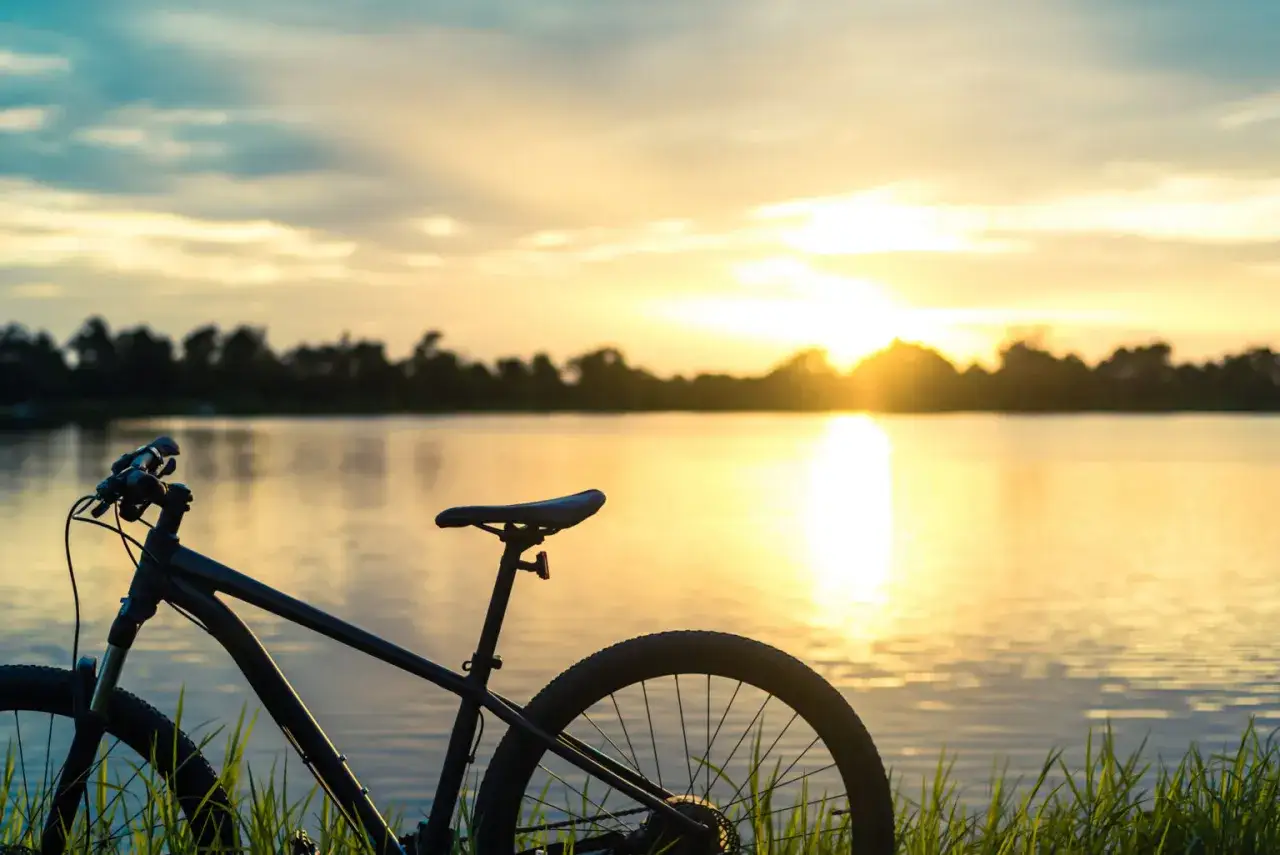 Rower na tle zachodzącego słońca nad jeziorem. Idealne miejsce na odkrywanie tras rowerowych Mazur.