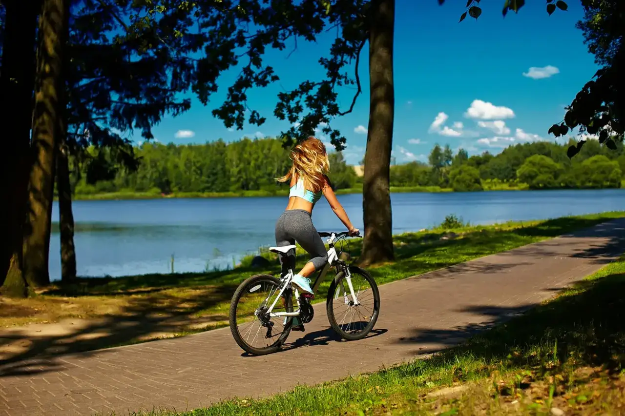 Kobieta na rowerze podziwia malownicze trasy rowerowe Mazury nad jeziorem.