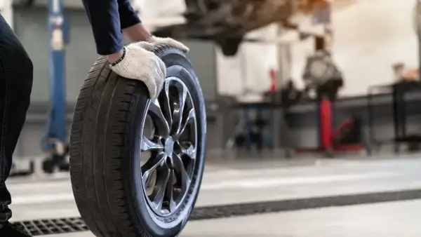 Mechanik w rękawiczkach trzyma oponę. Czy opony rowerowe do miasta z gładkim bieżnikiem zużywają się szybciej na kostce i asfalcie?